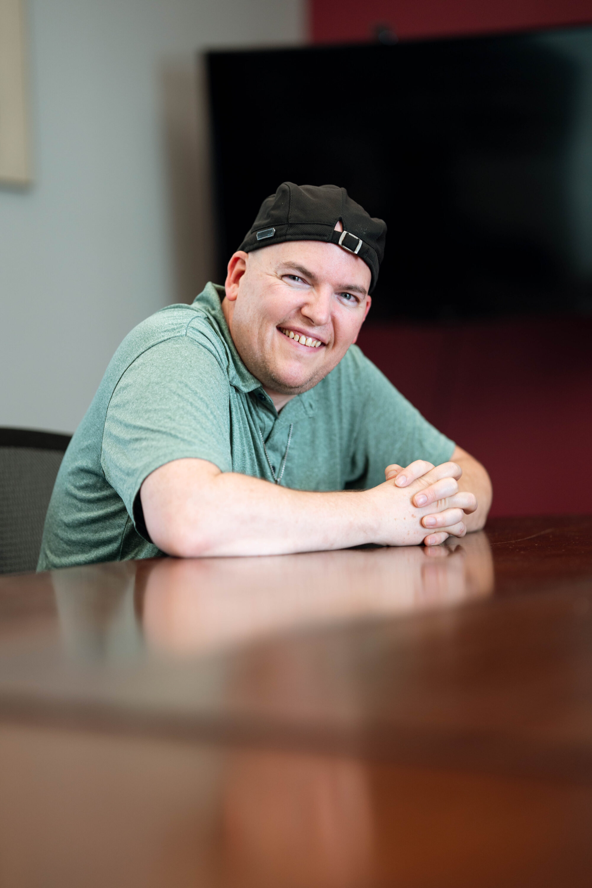 Smiling person sits at a conference table.