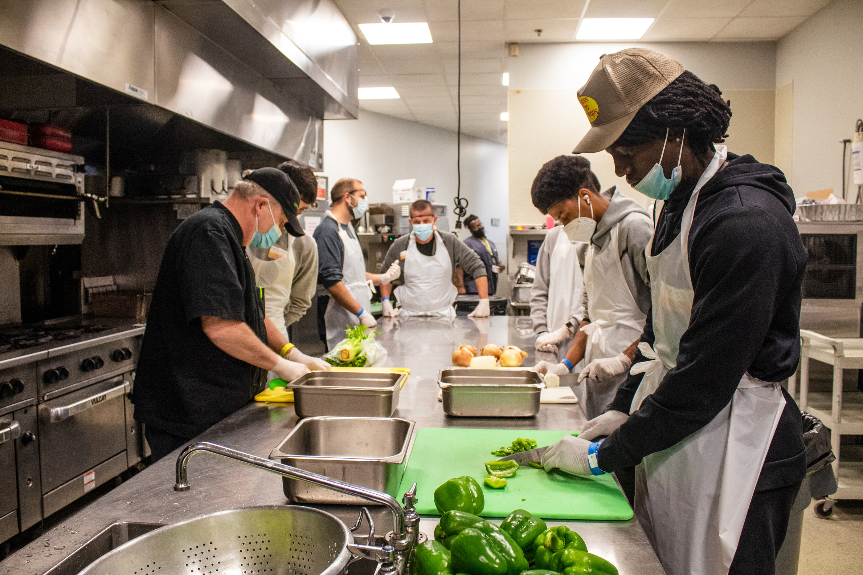 People preparing vegetables in a commercial kitchen.