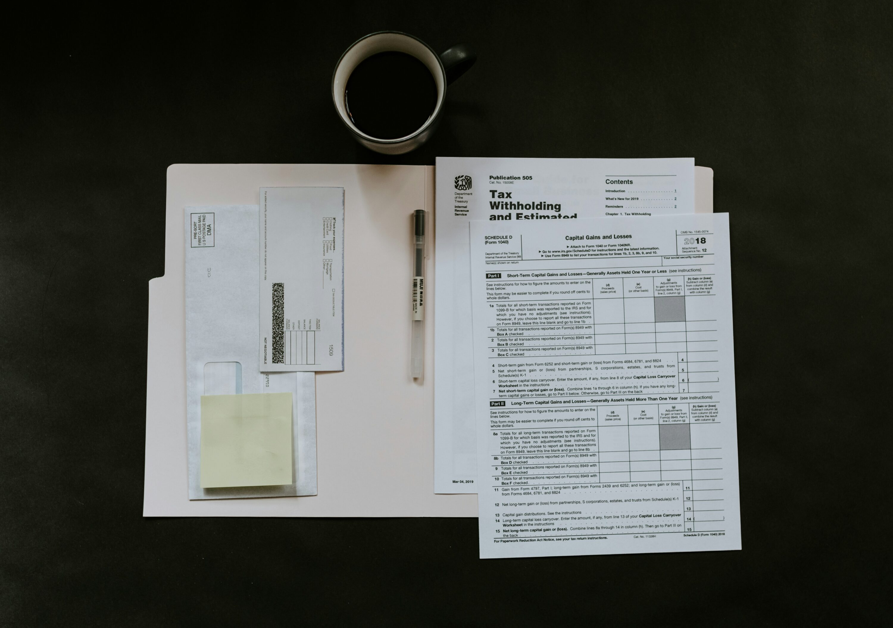 Tax documents on table with coffee and pen.