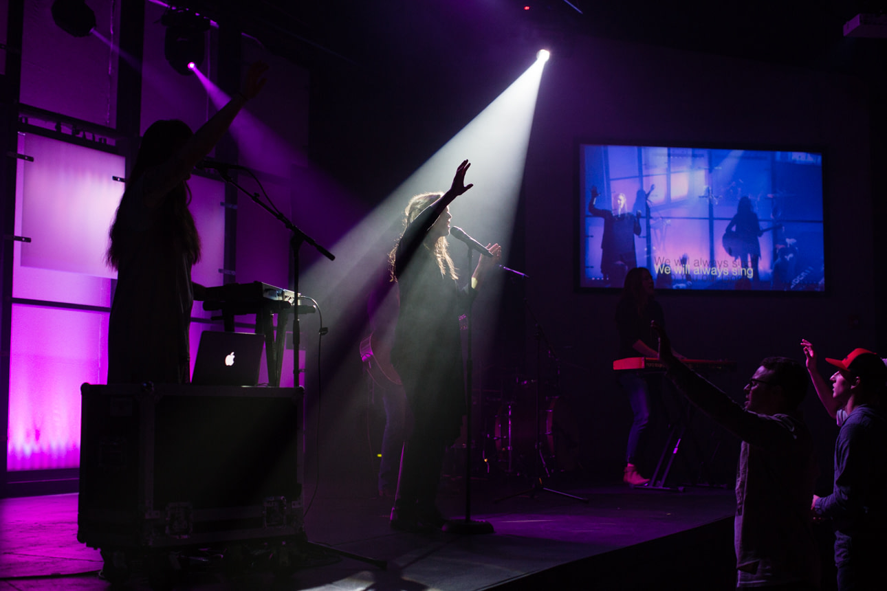 Person worshipping on stage under a spot light