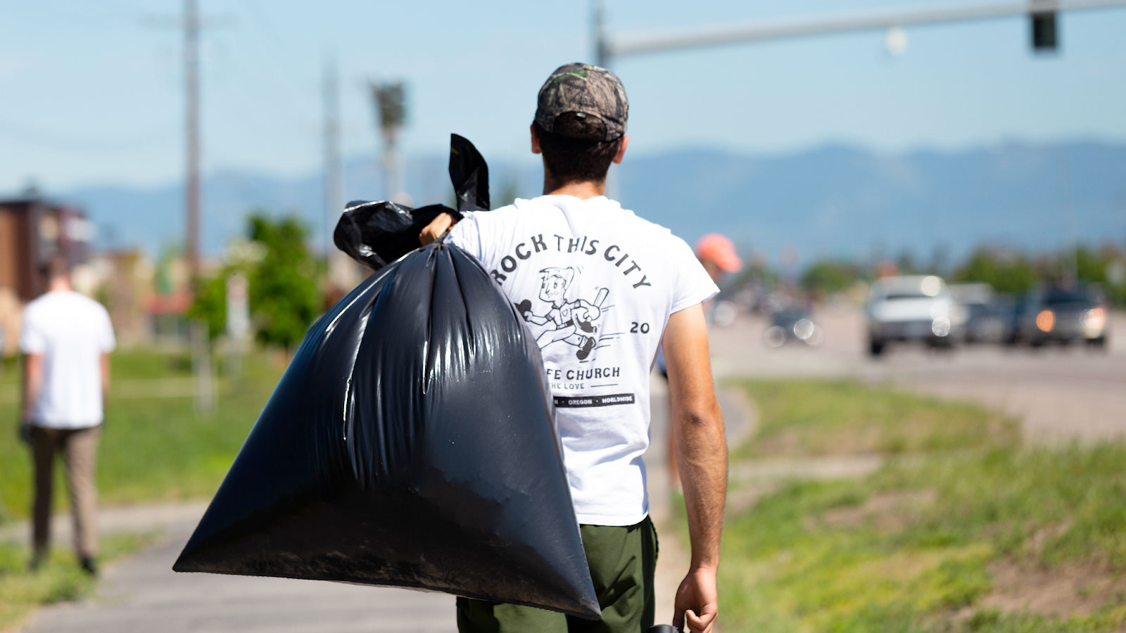 Volunteer cleaning up trash along roadside.