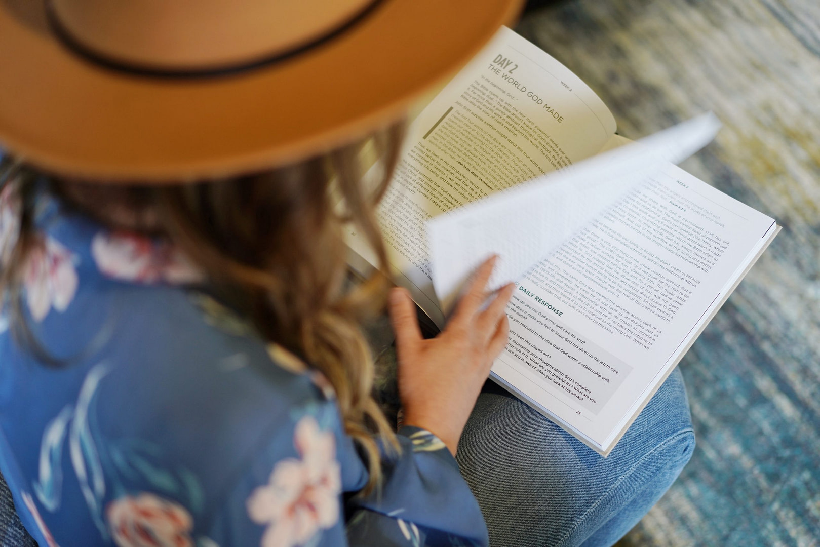 Girl with a brown hat looking down flipping the page of a book