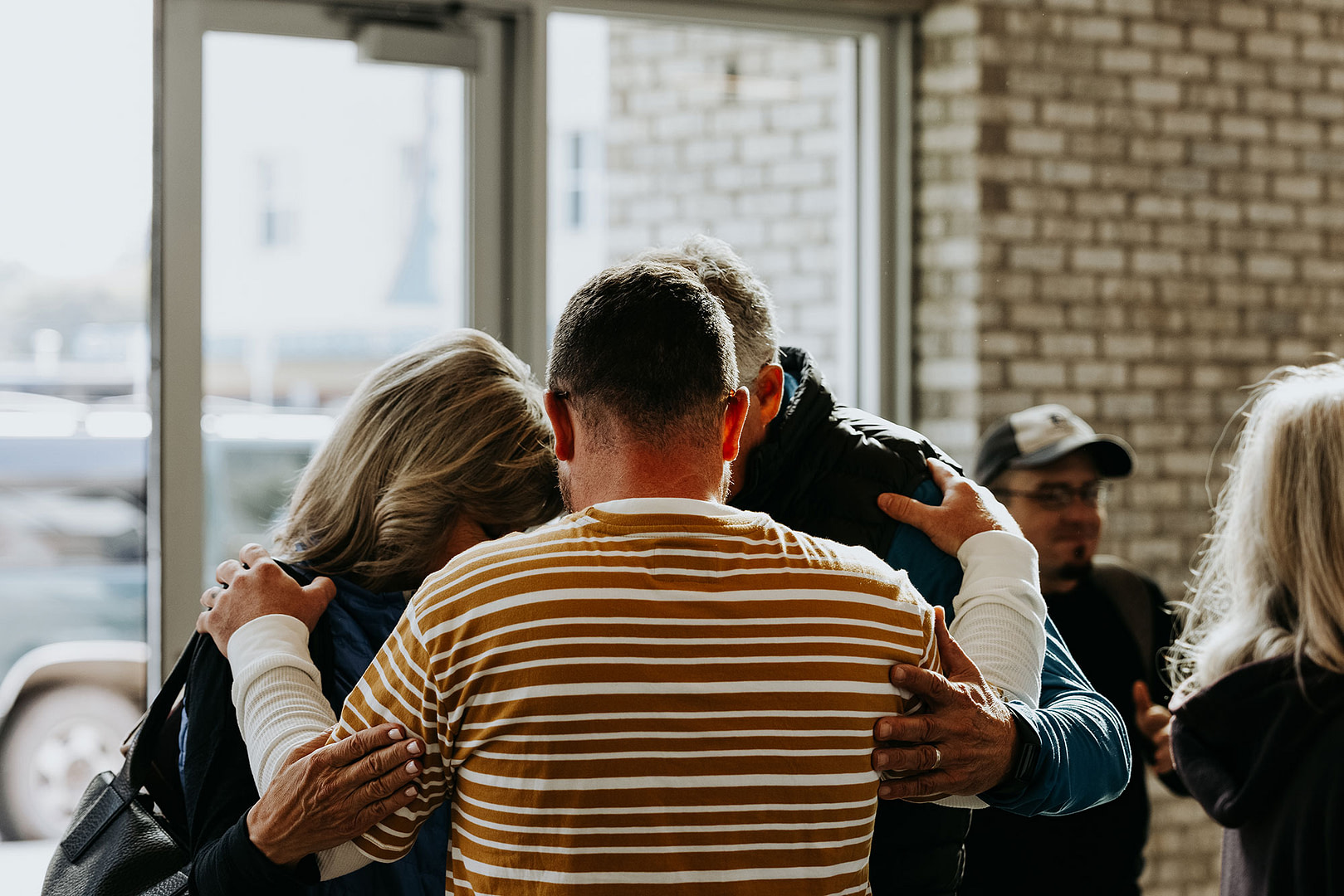 Three people with their hands on each other's shoulders praying