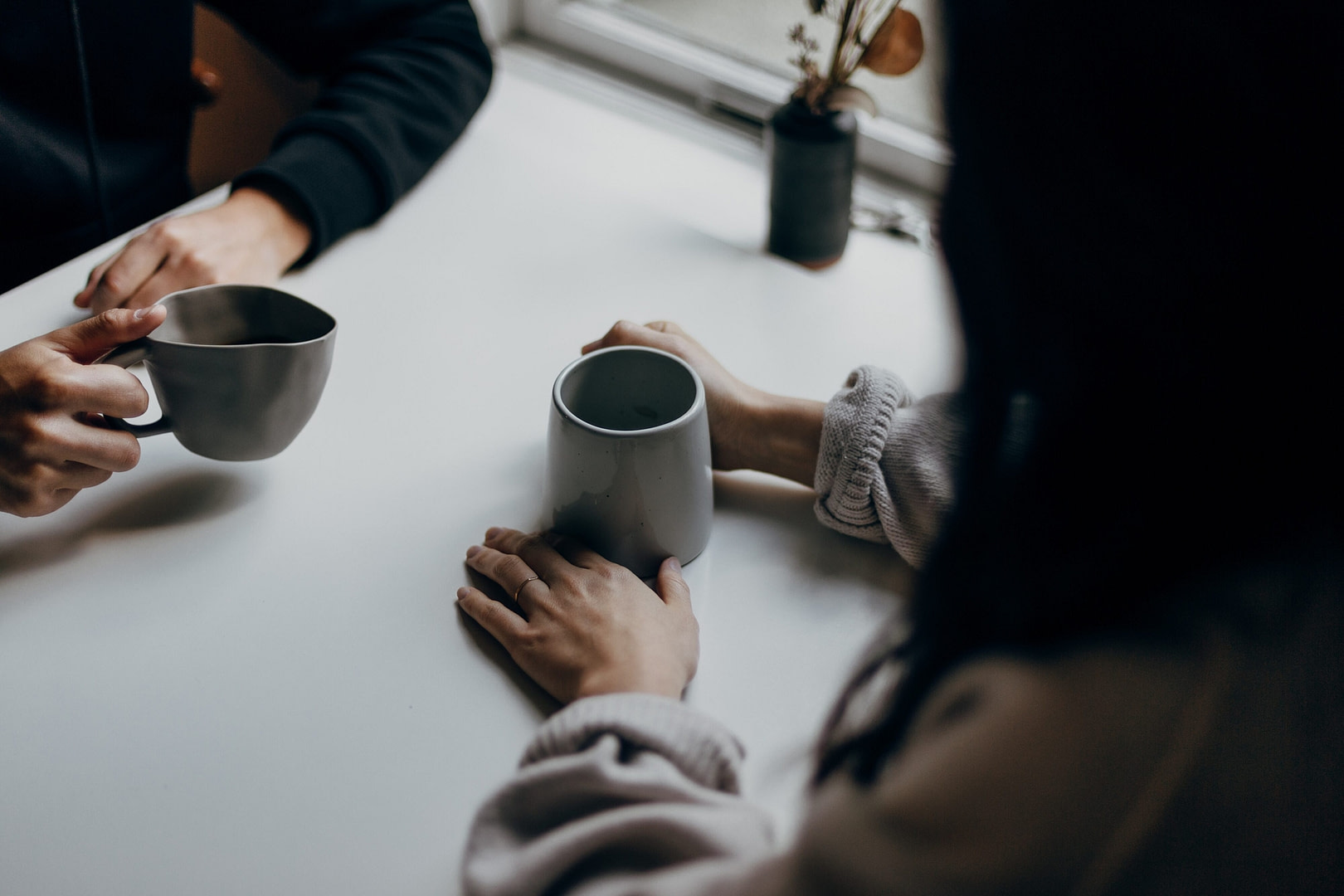 Hands holding coffee cups on a table