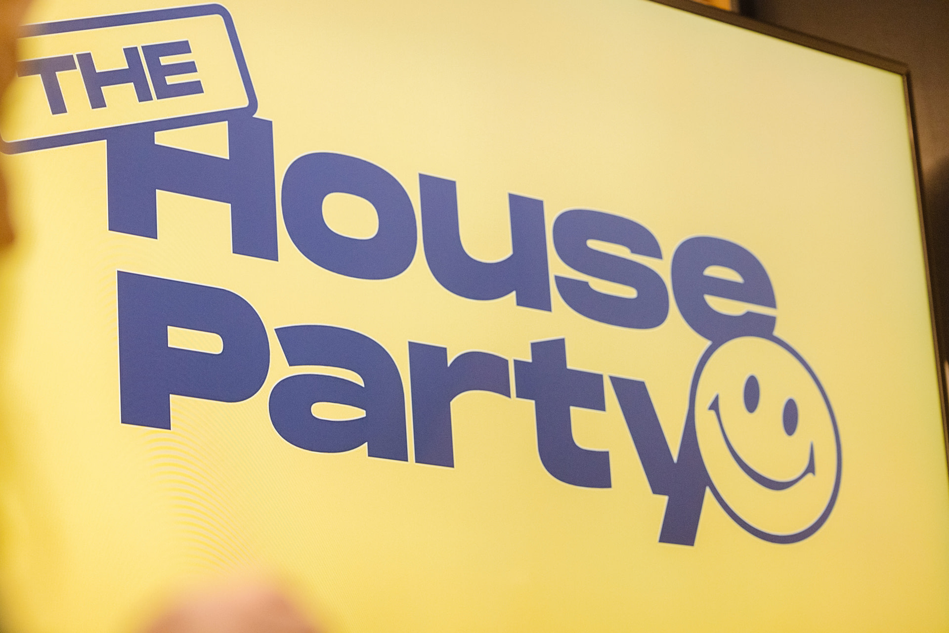A yellow sign with a smiley face that says The House Party