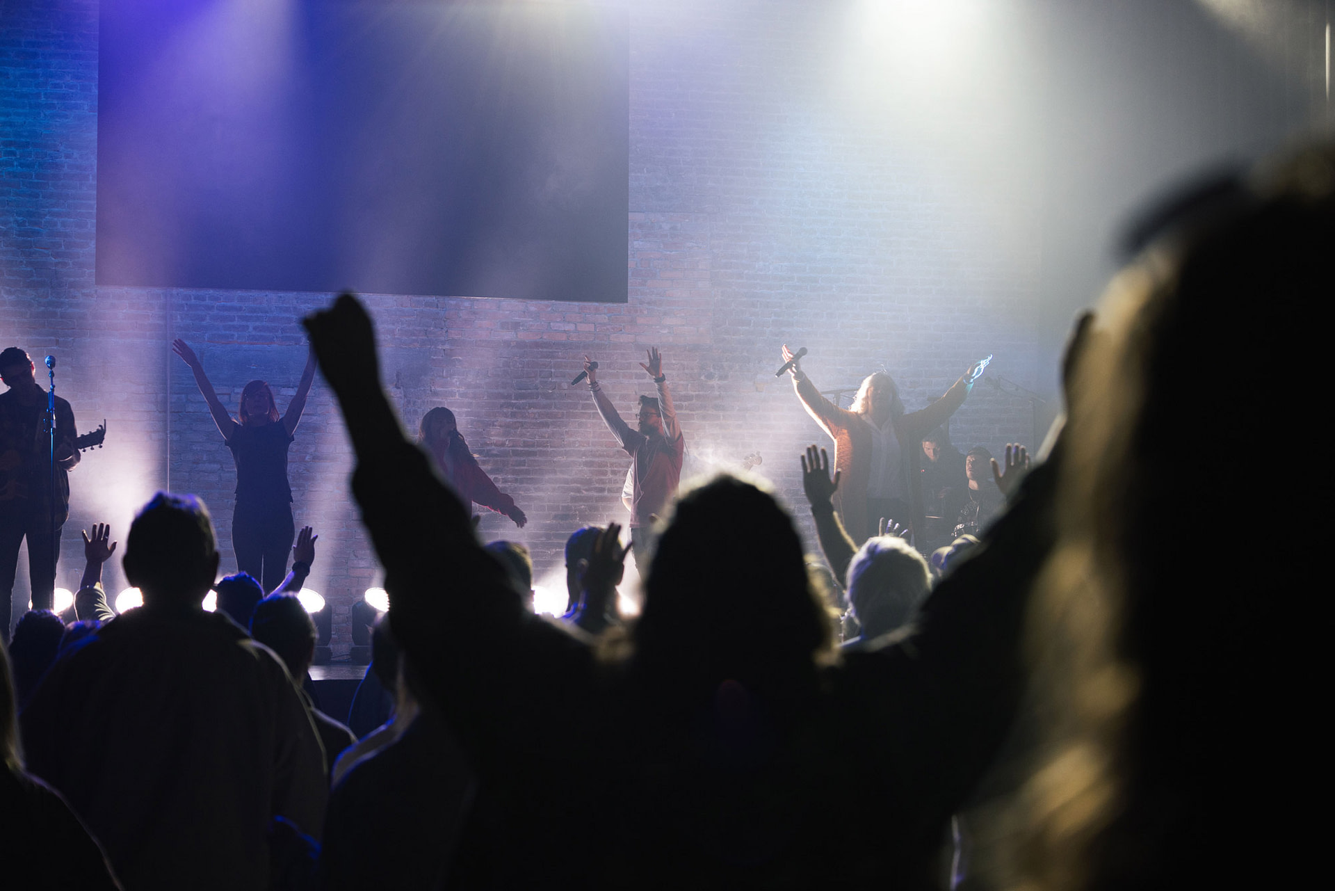 Worshipers with their hands raised at a concert