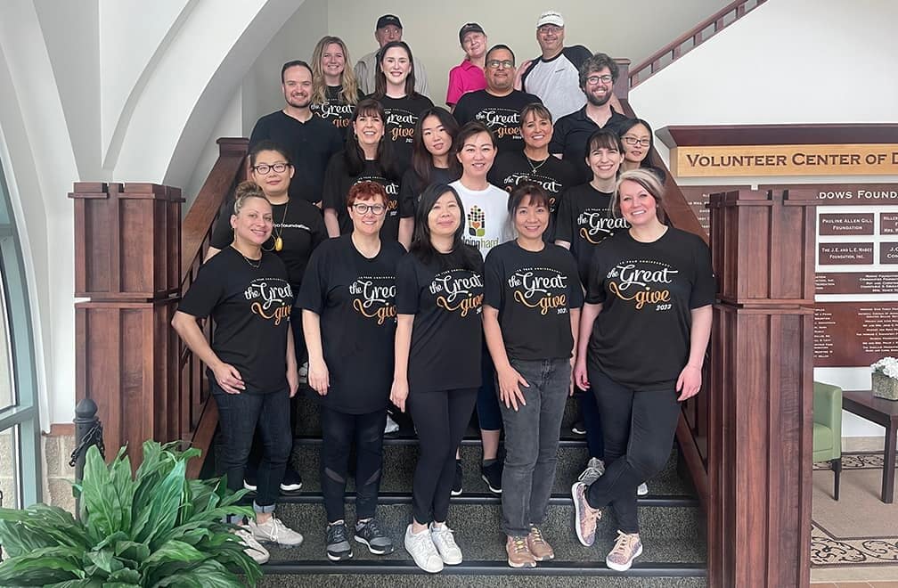 Group in matching shirts on staircase at event.