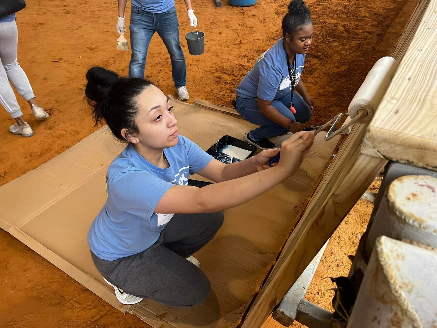 Volunteers paint a wooden structure.