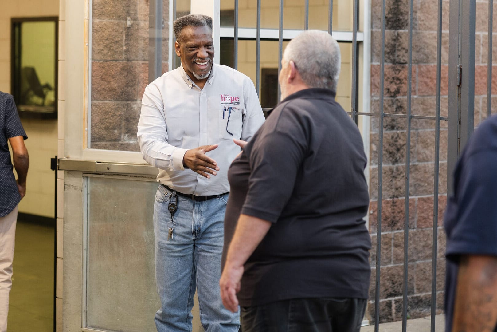 Smiling people shaking hands outside a building entrance.