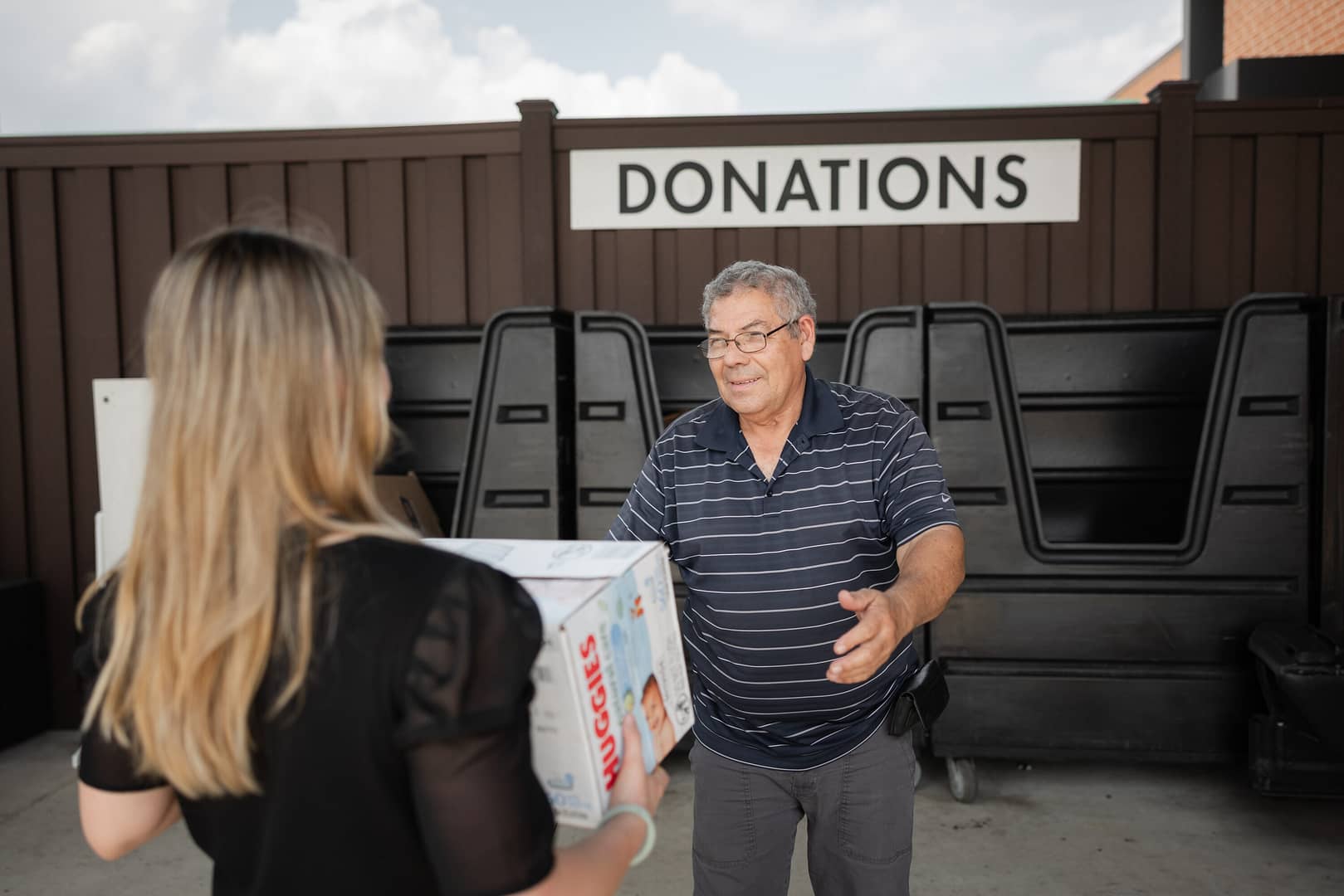 People exchanging donation box at donation center.