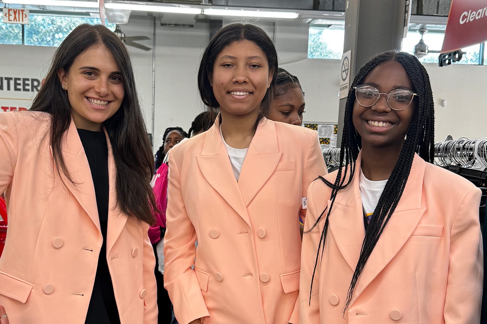 Smiling women in matching peach blazers.