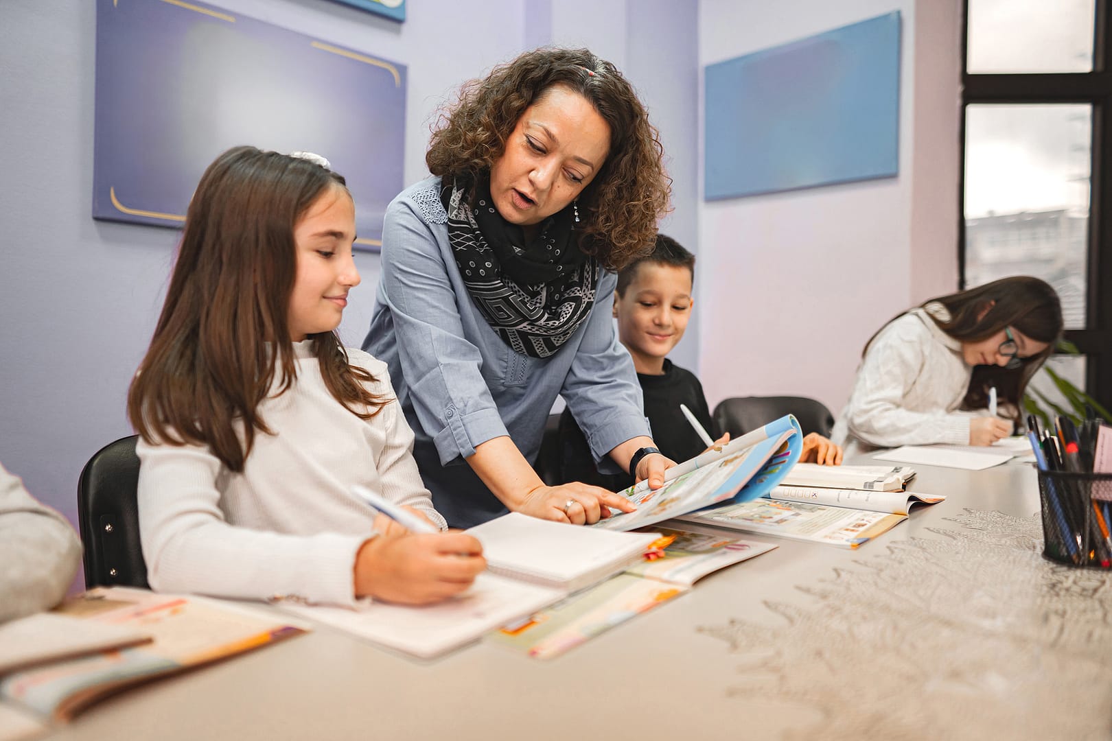 Teacher assisting students with classwork at desk.