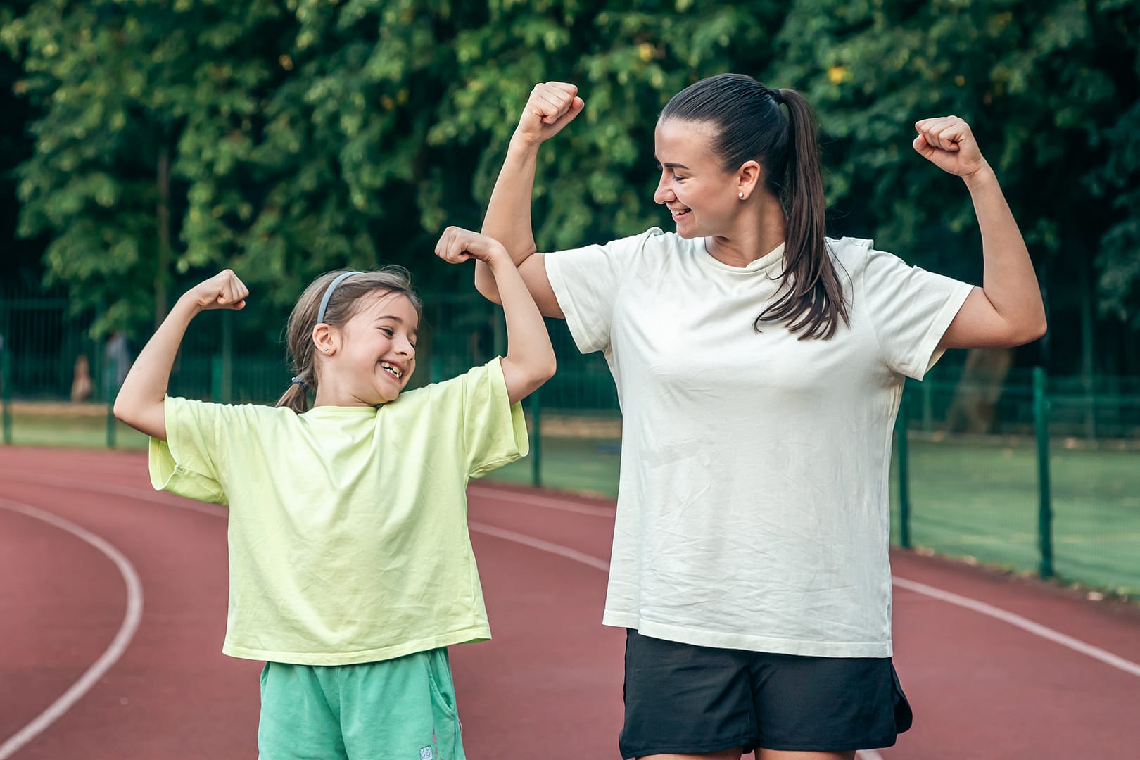 Mother and daughter flexing muscles on track