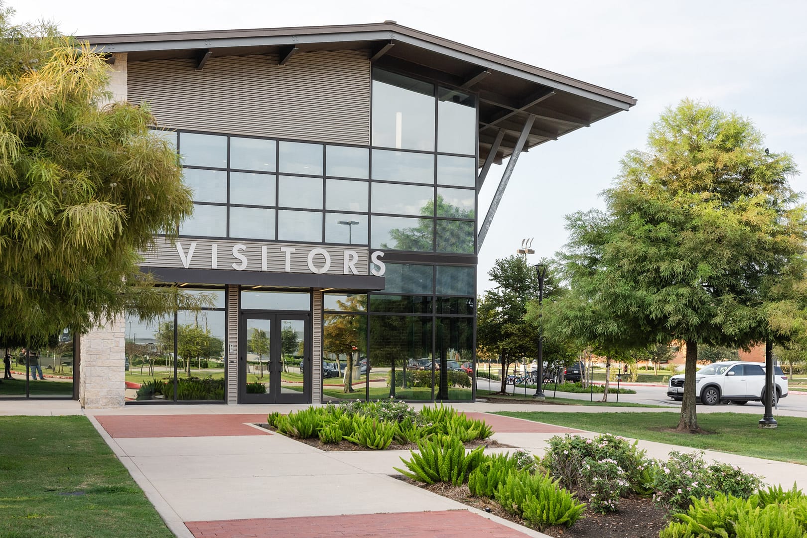 Modern visitor center with glass facade and greenery.