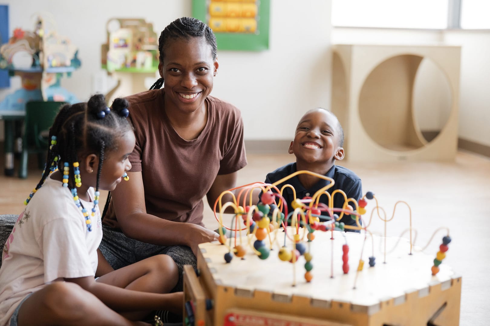 Smiling children and teacher with educational toy.