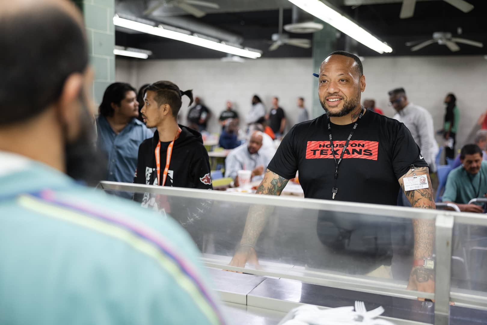 Man smiling at counter in crowded room.