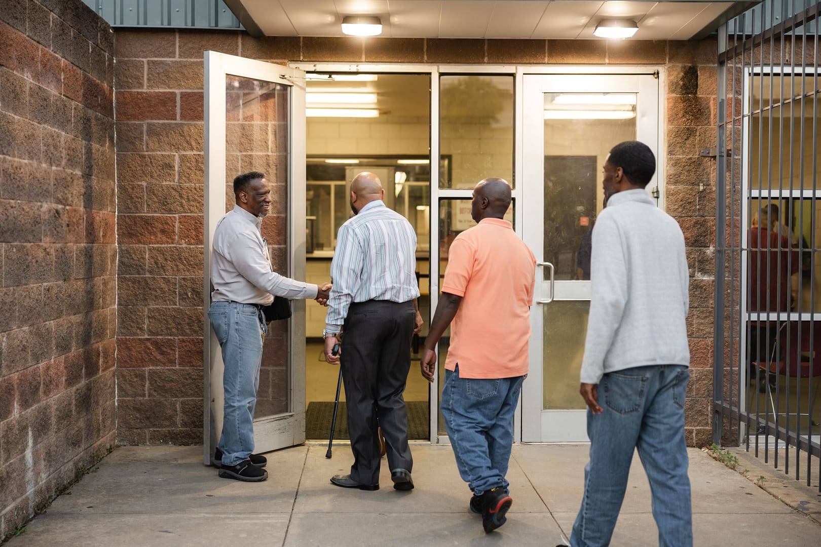 Men entering a building, shaking hands