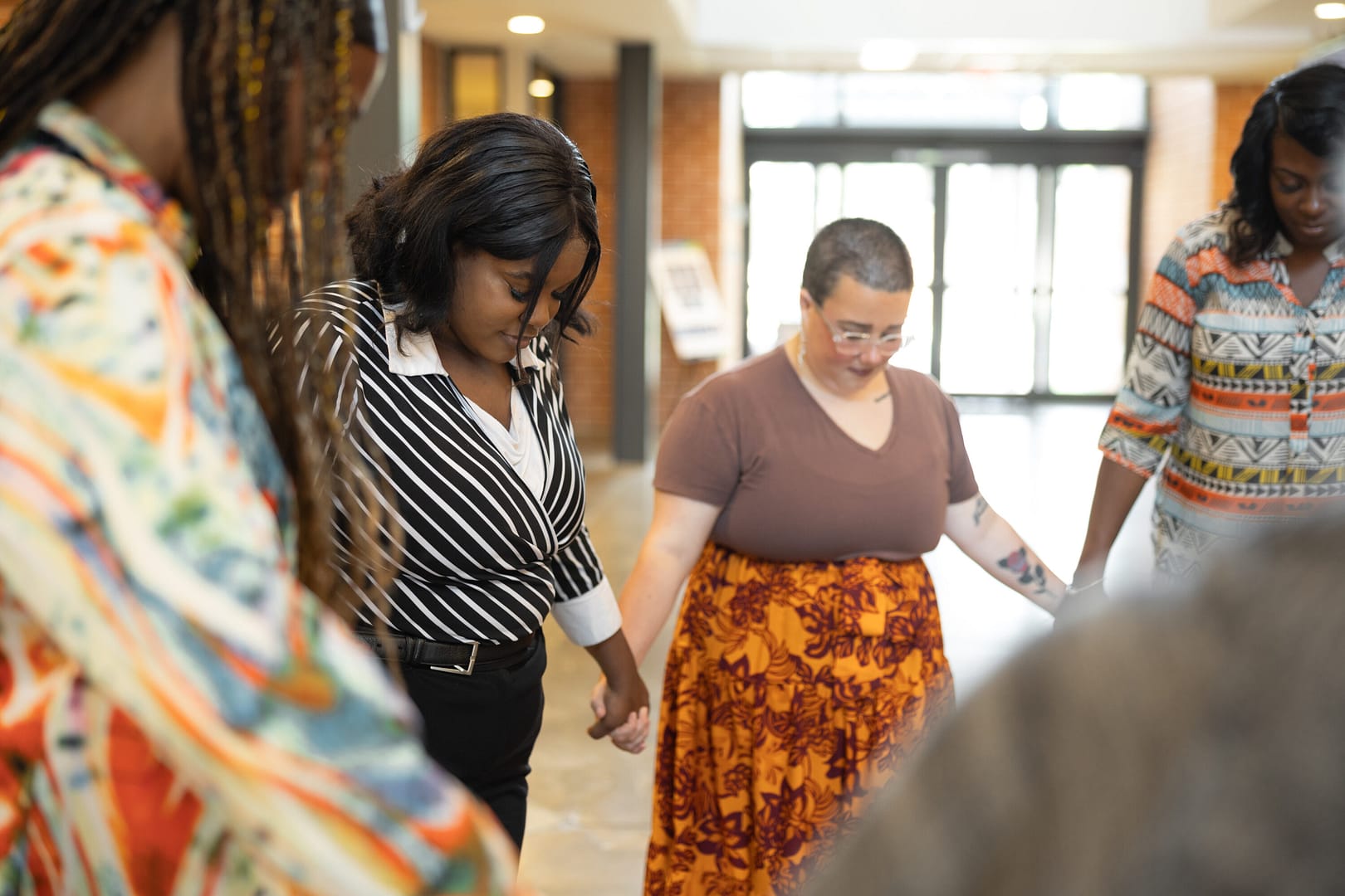 Diverse group holding hands in a circle indoors.