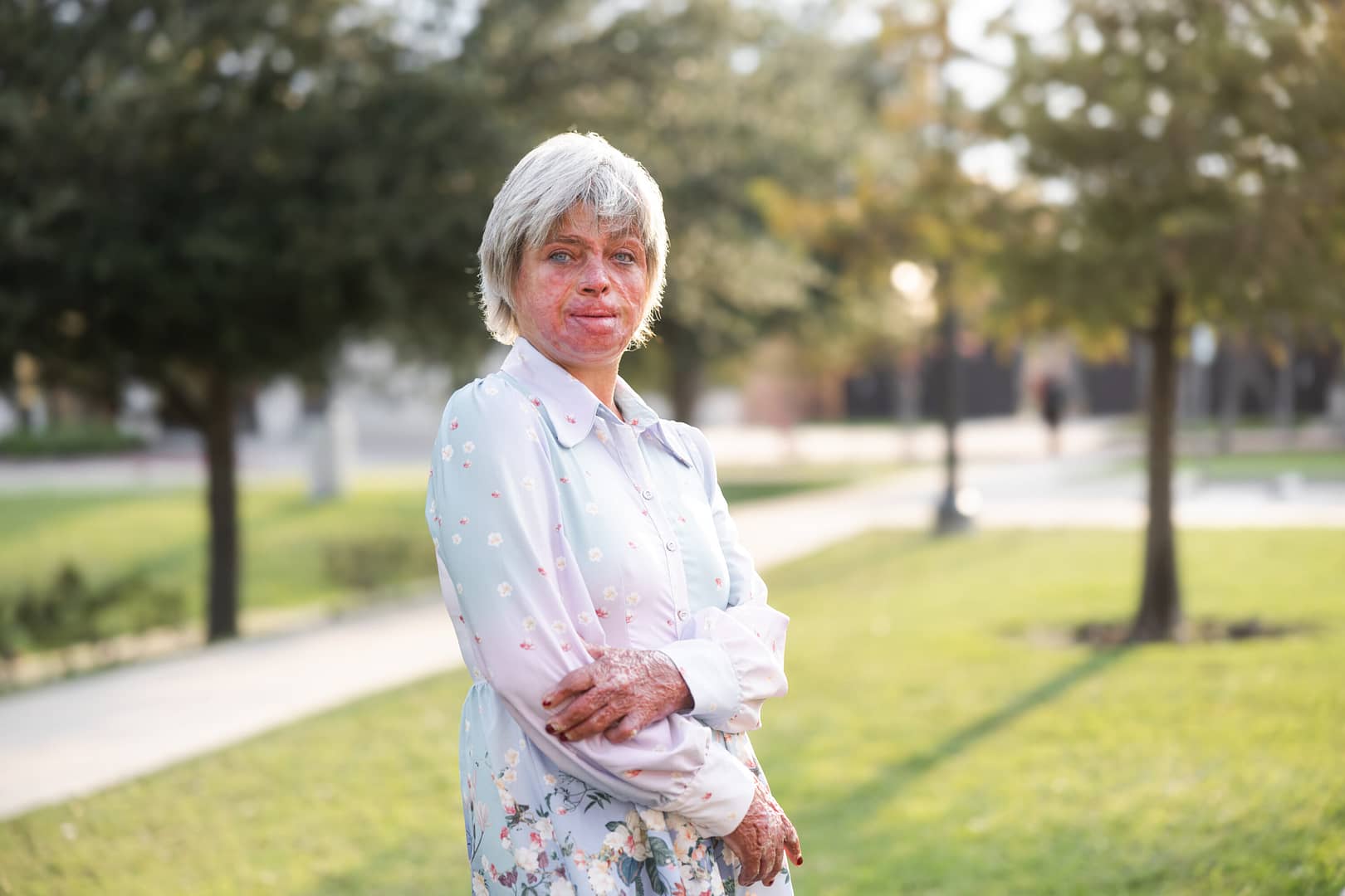 Smiling woman standing in sunlit park