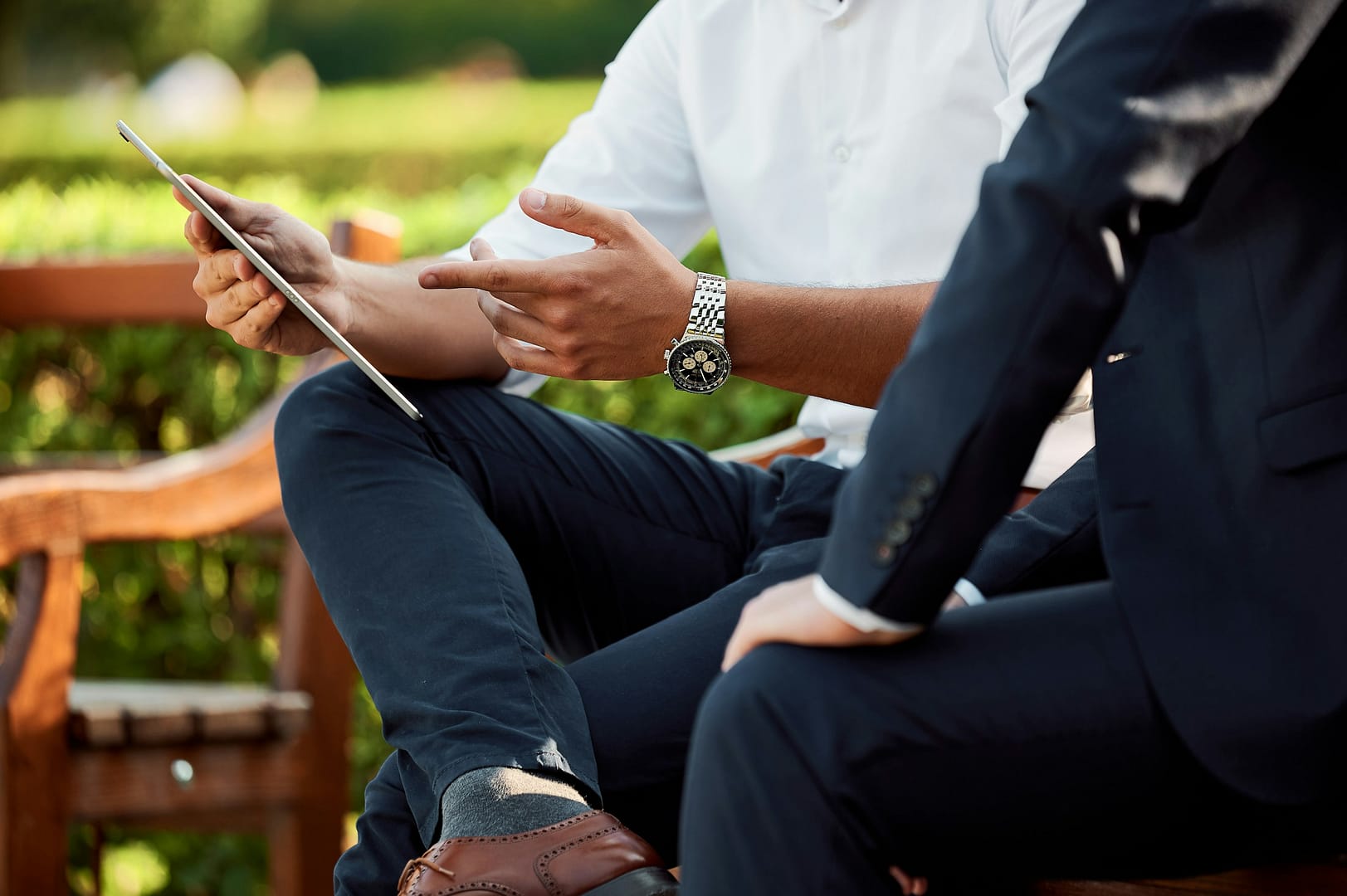 Two men discussing with a tablet outdoors