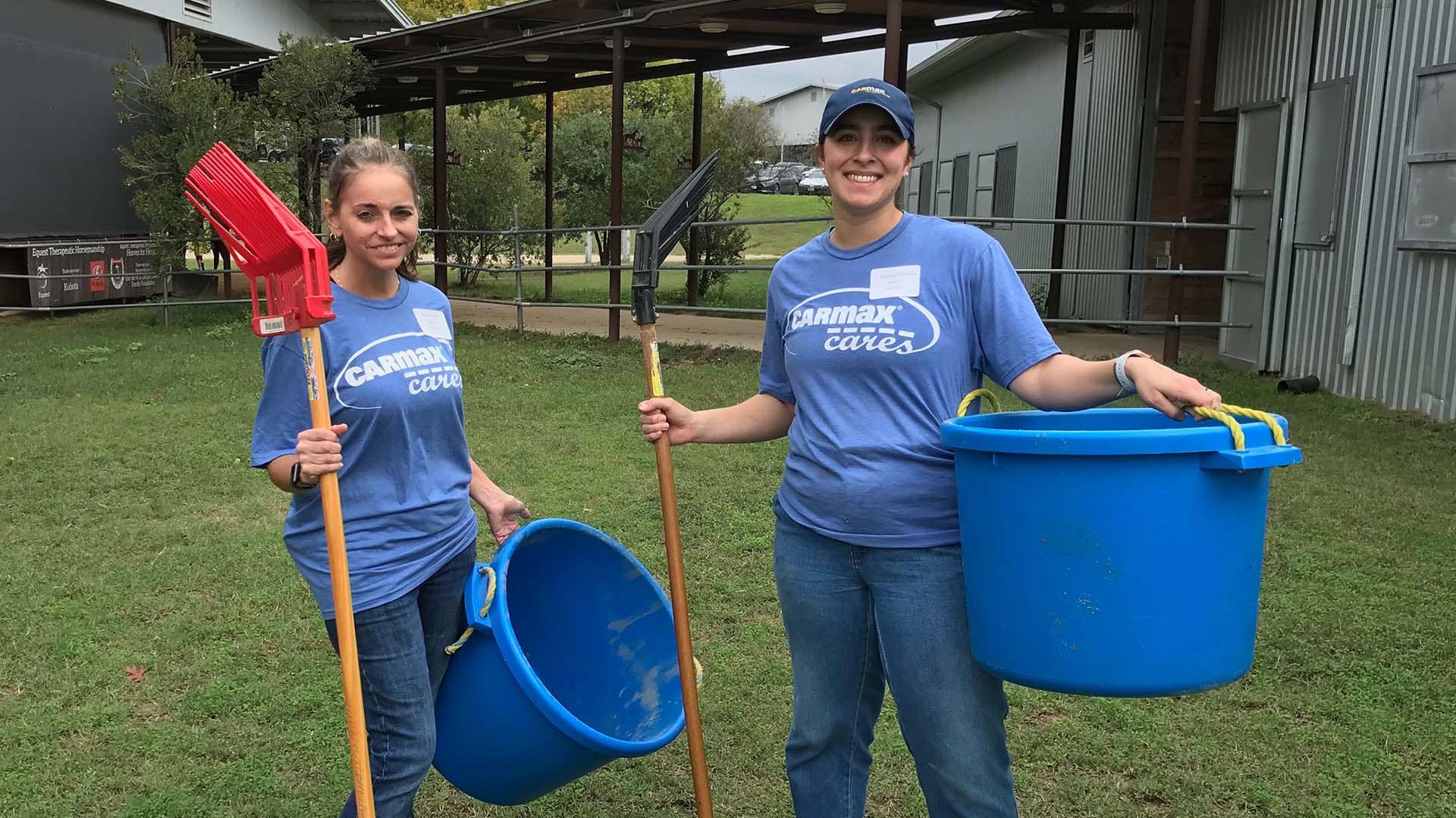 Two volunteers with cleaning tools and buckets outside.
