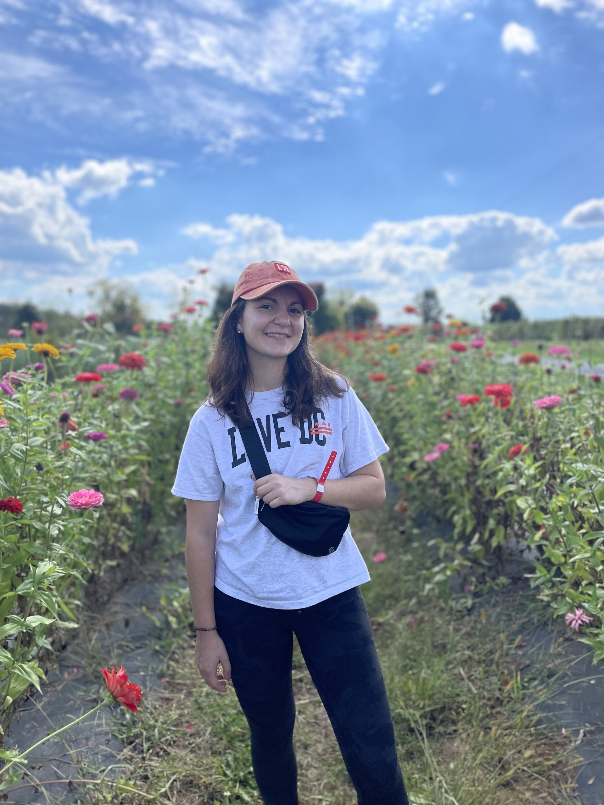 Person in field of colorful flowers under blue sky.