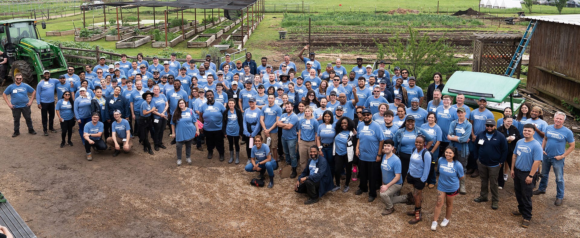 Large group wearing blue shirts at a farm gathering.