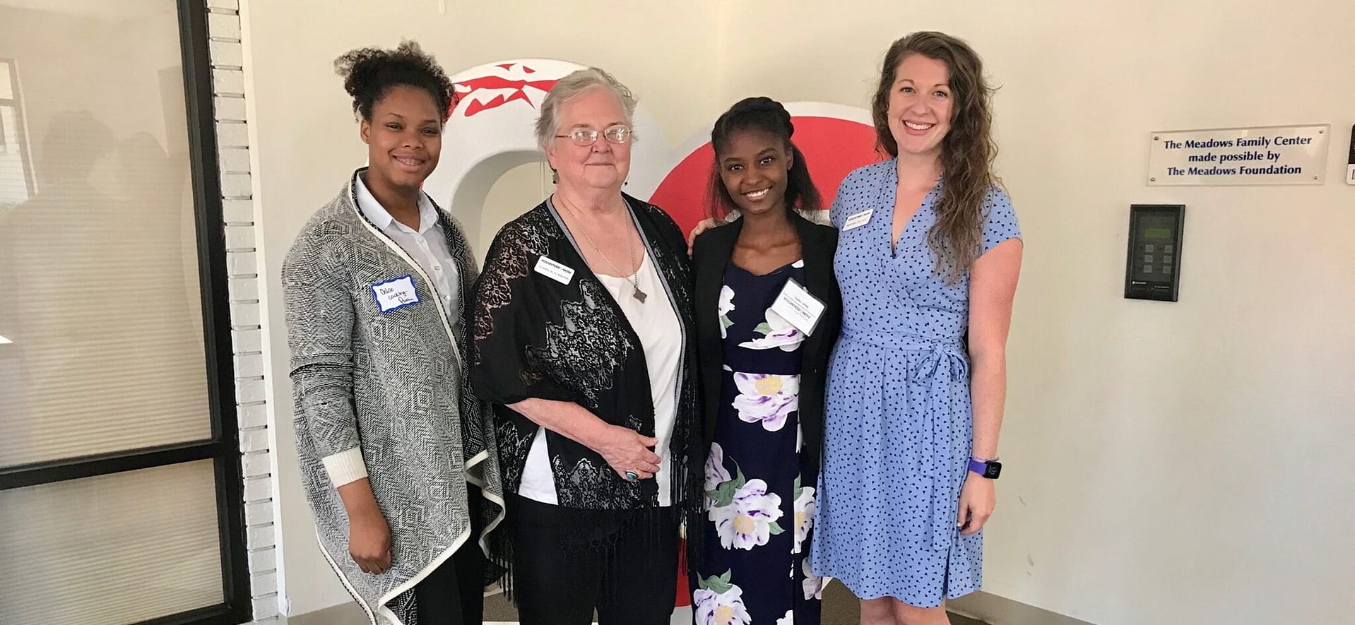 Four women posing together at The Meadows Family Center, wearing name tags and professional attire