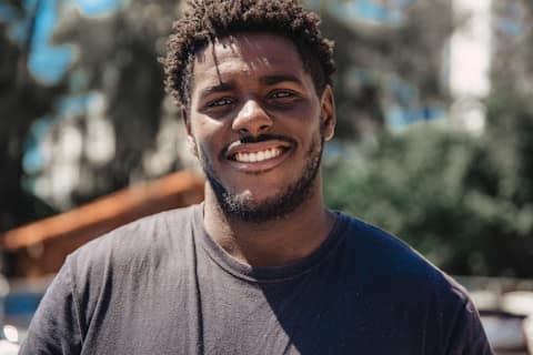 Smiling person standing outdoors with trees background