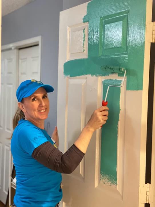 Person painting a door turquoise.