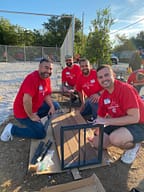 Volunteers assembling furniture outdoors at event.