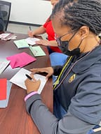 People writing holiday cards at a table.