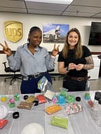 Two women crafting with colorful supplies at UPS office.
