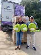 Two people holding stuffed toys by donation truck.