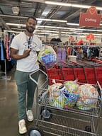 Man with shopping cart in clothing store.