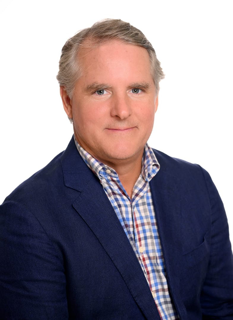 Man in blue suit, checkered shirt, smiling