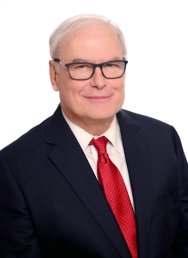 Man in suit and red tie smiling.