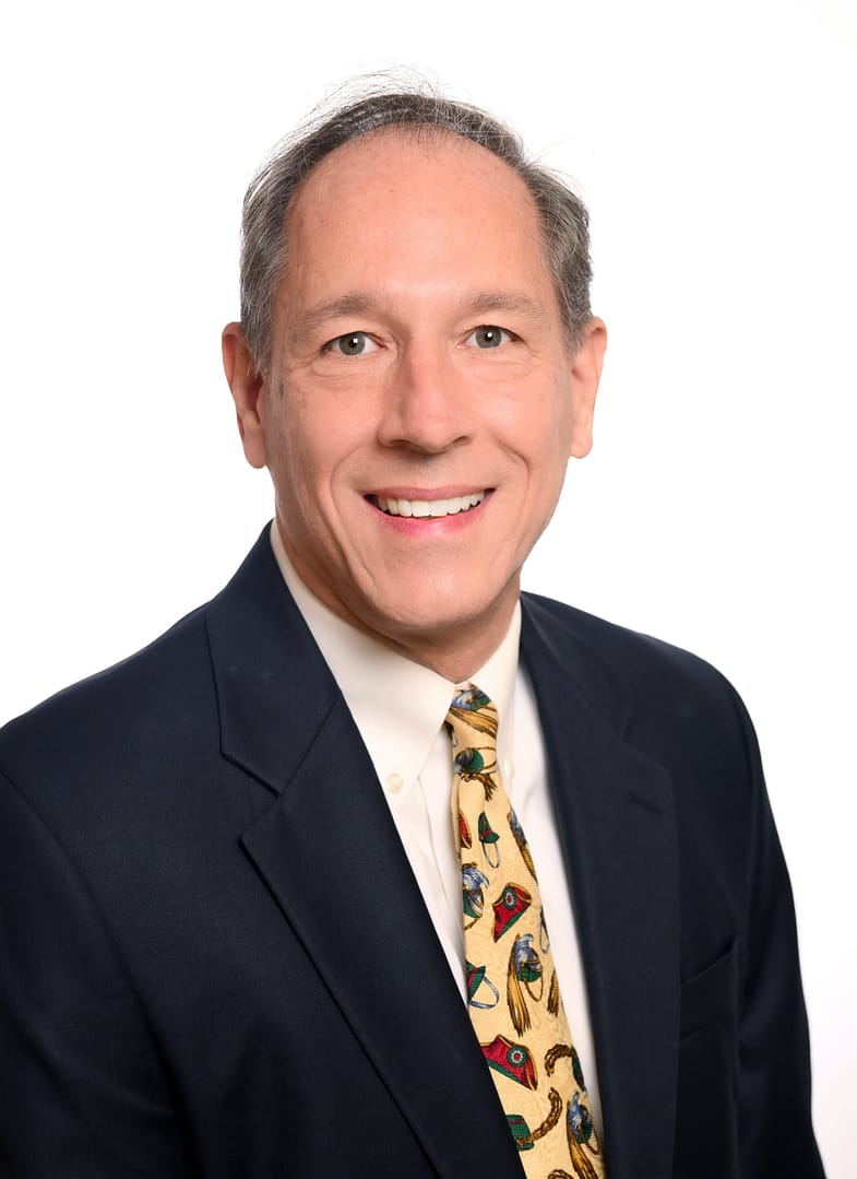 Smiling man in suit with colorful tie.