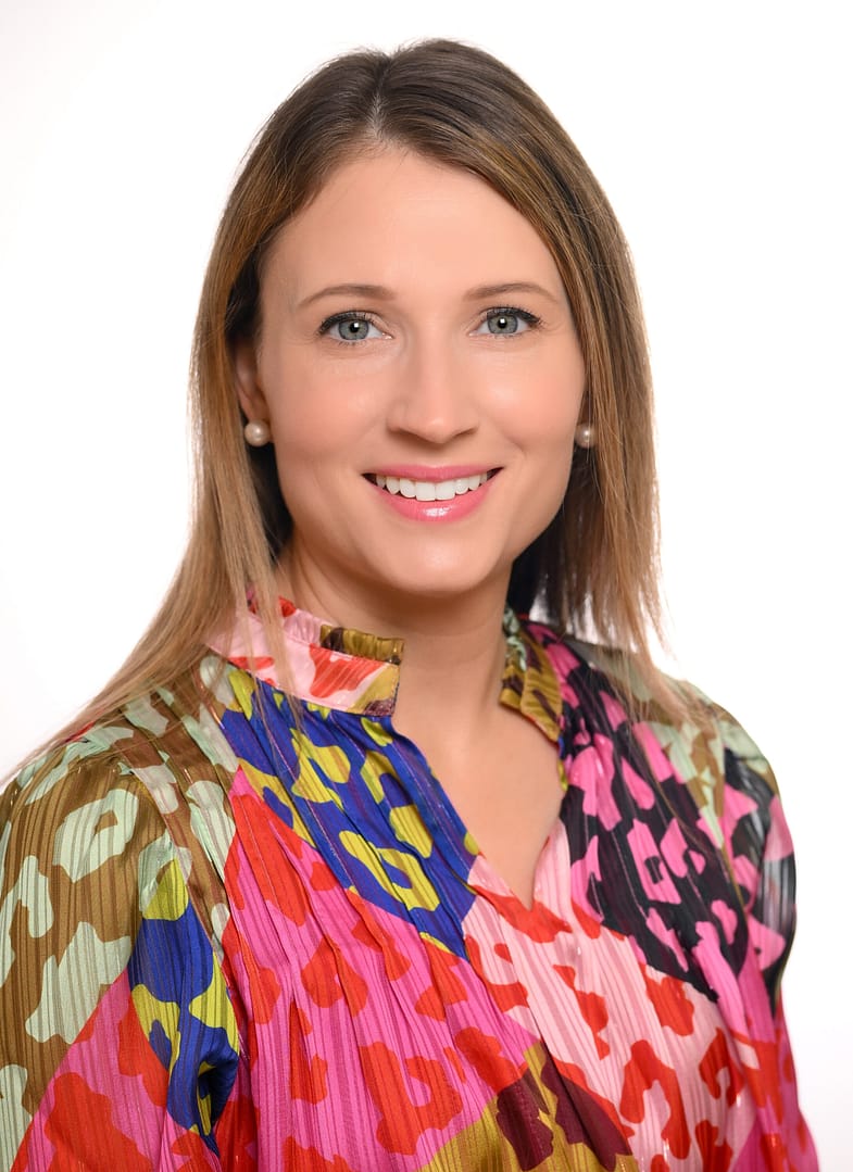 Person smiling in colorful patterned blouse.