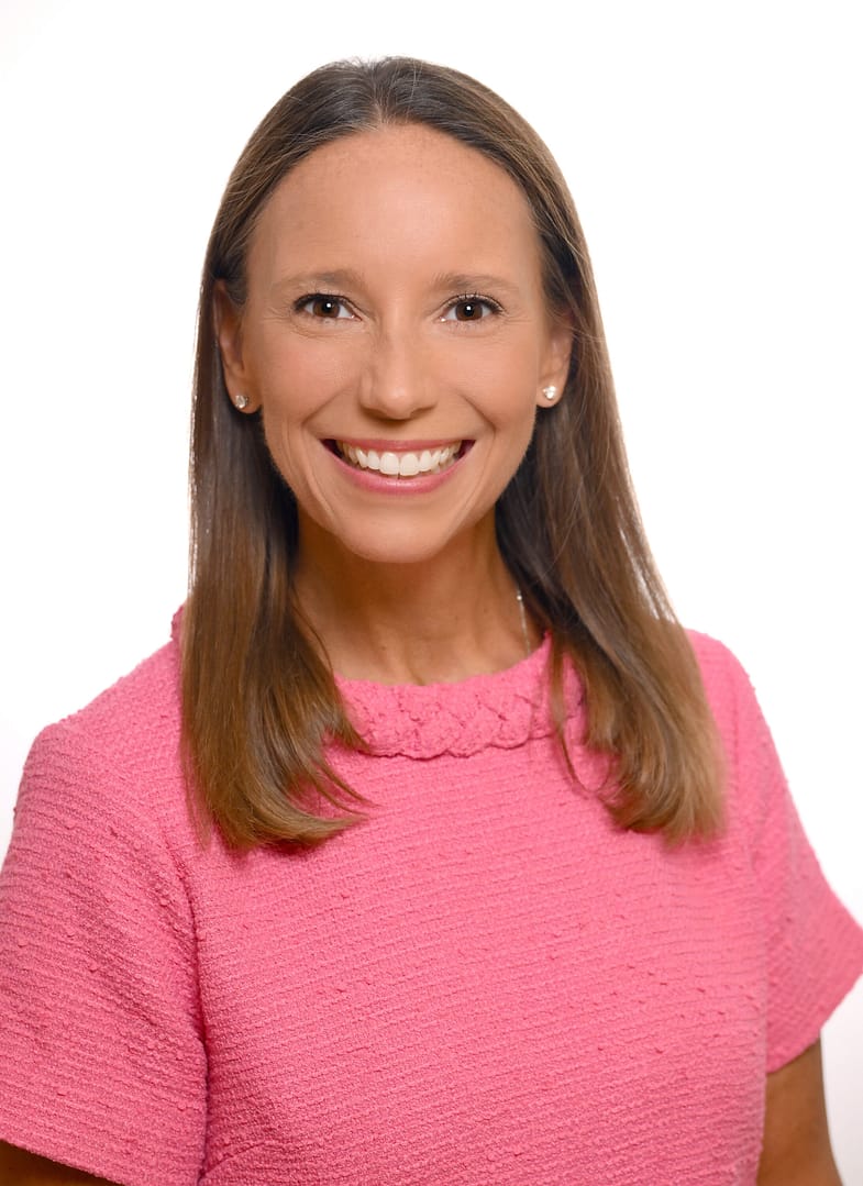 Smiling woman in pink attire against white background.