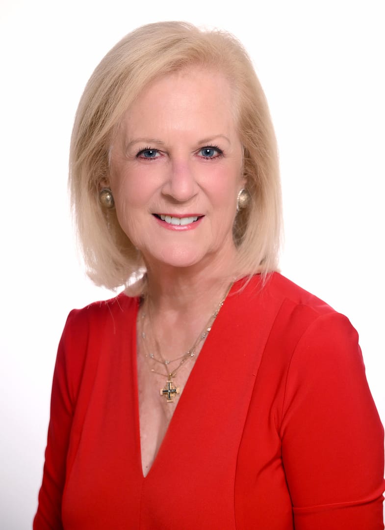 Smiling woman in red blouse and jewelry.