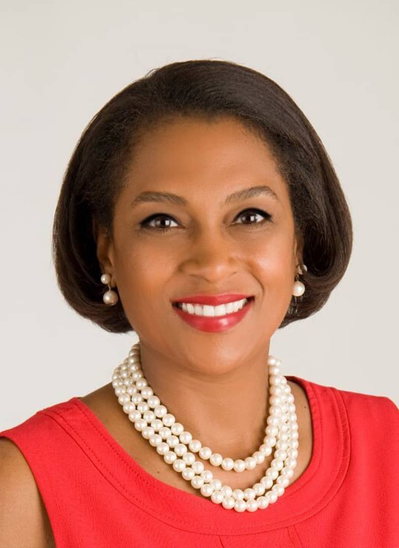 Woman smiling in red dress with pearl necklace.