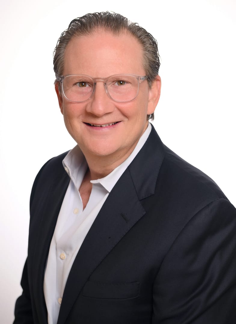 Smiling person in suit with glasses, professional portrait.