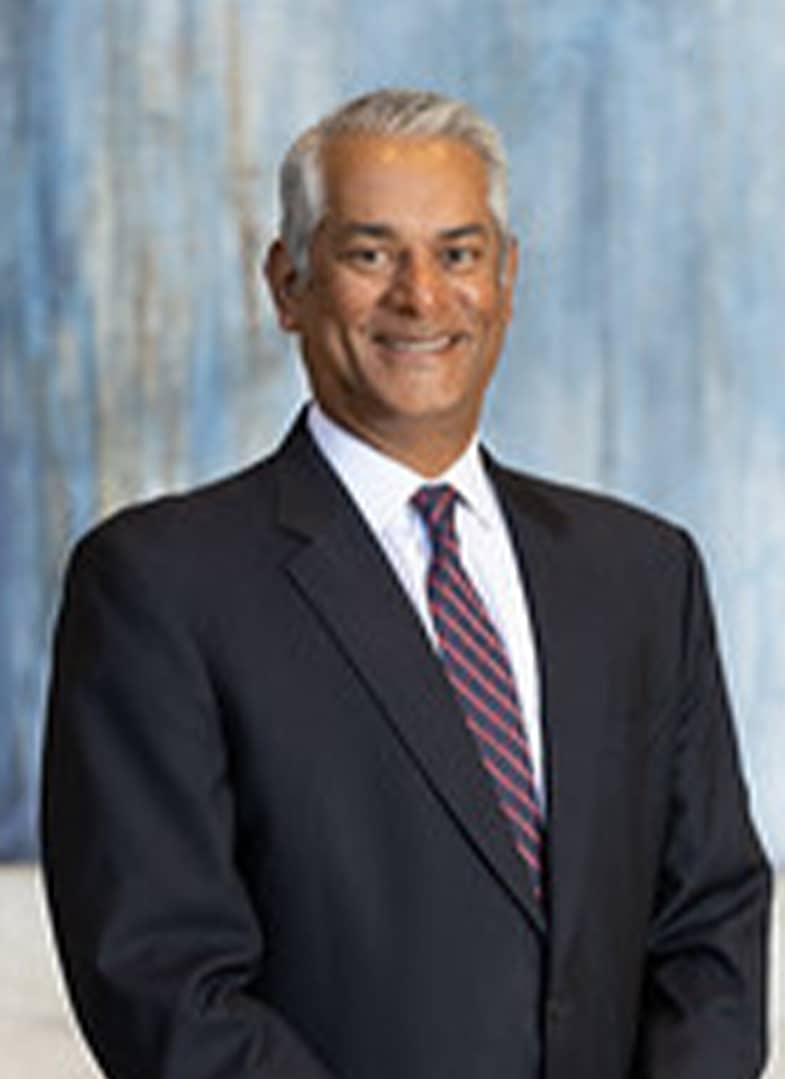 Man in suit smiling against blue background.