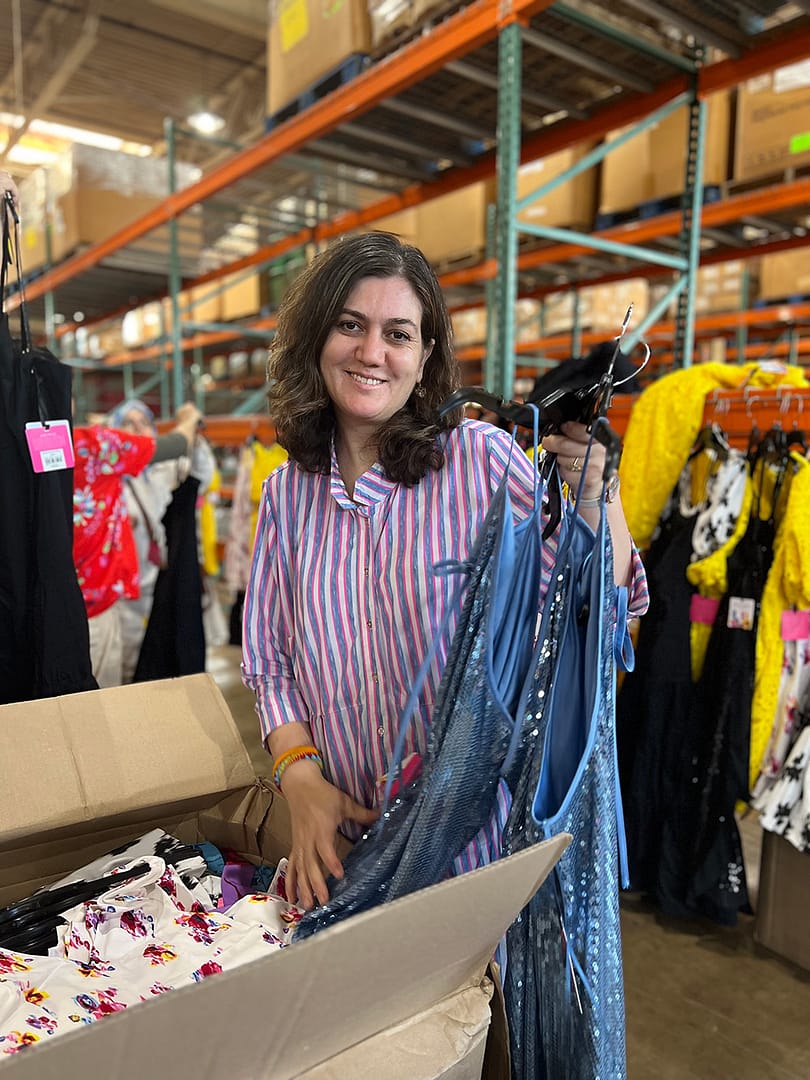 Person sorting dresses in warehouse setting.
