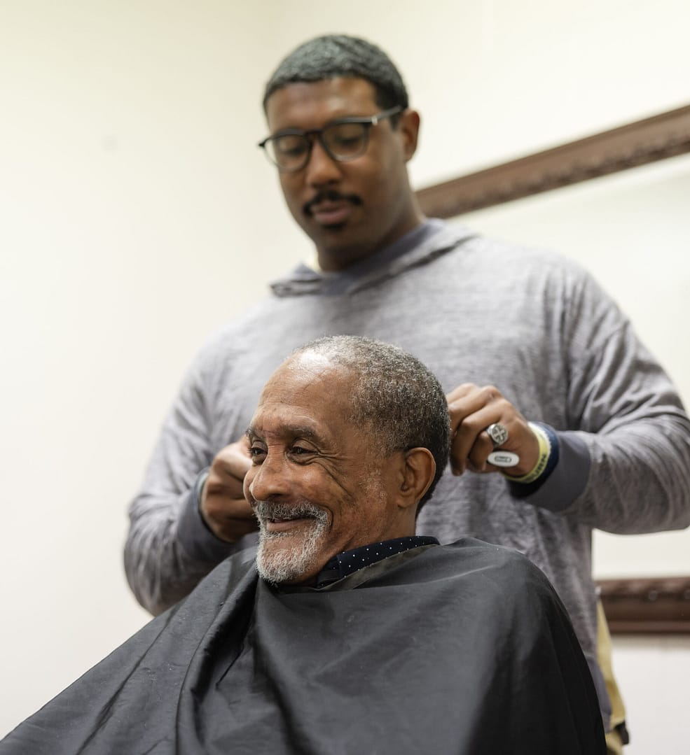 Barber cutting an elderly man's hair.